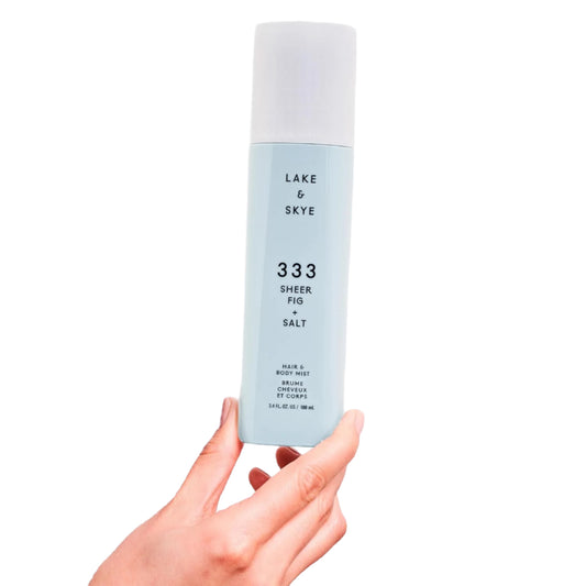 Hand holding a bottle of Lake & Skye sheer fig and salt product against a white background