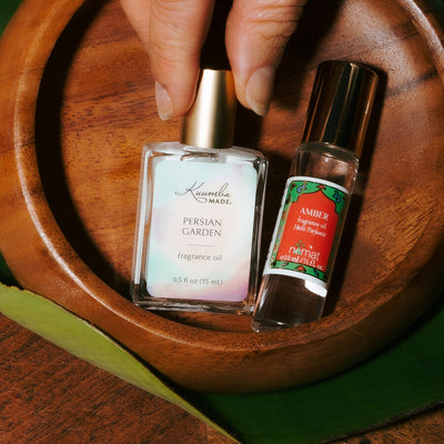 Kuumba Made Persian Garden and Nemat Amber perfume oils in a wooden bowl